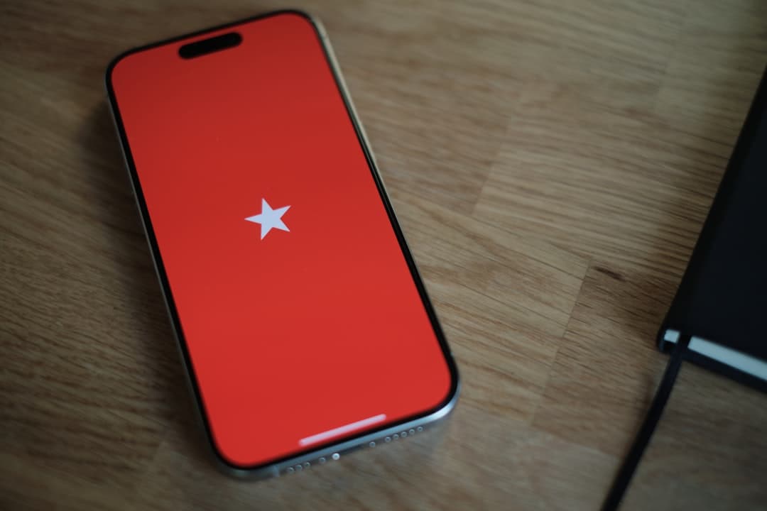 A red cell phone sitting on top of a wooden table